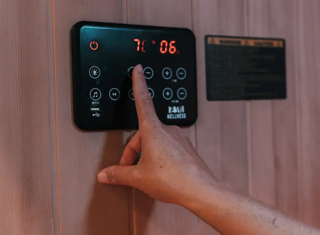 Persons hand adjusting the infrared sauna temperature panel inside the sauna.